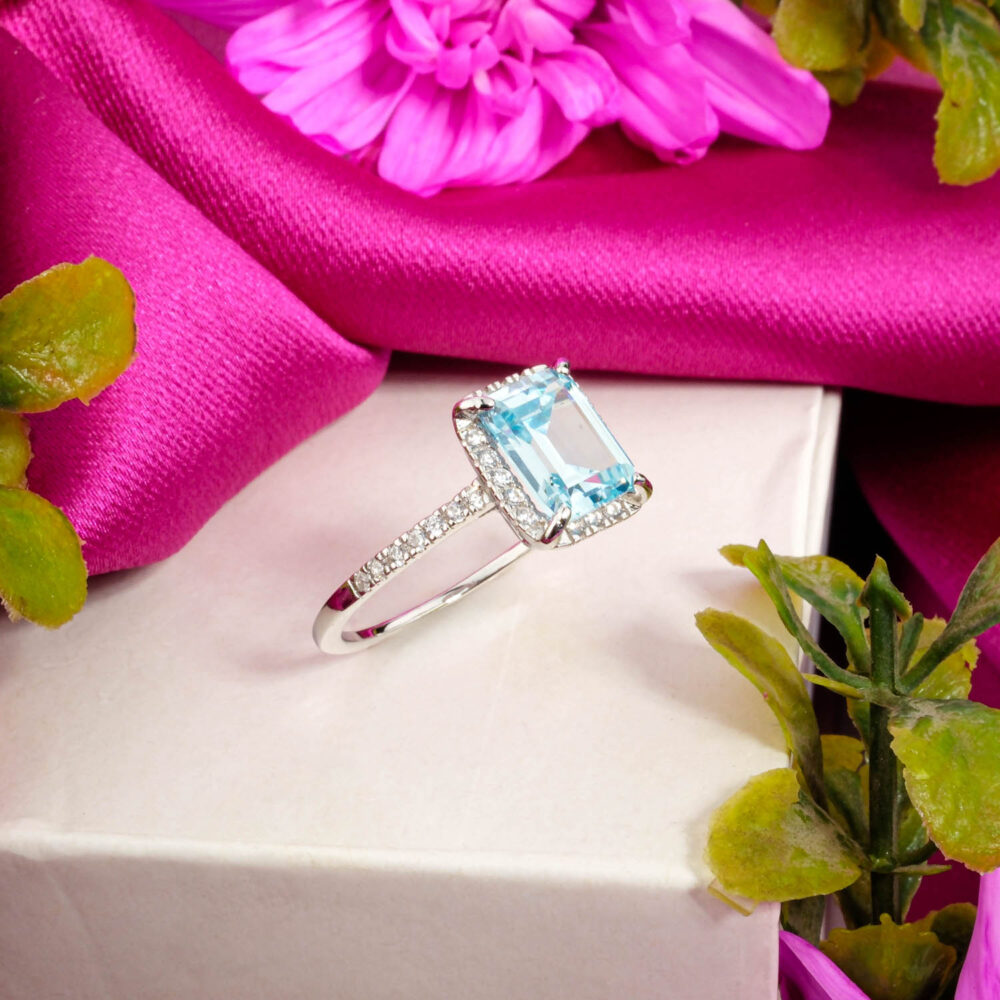 A designer 925 sterling silver ring featuring a cushion-cut Blue Topaz with a unique snowflake detail and baguette band.