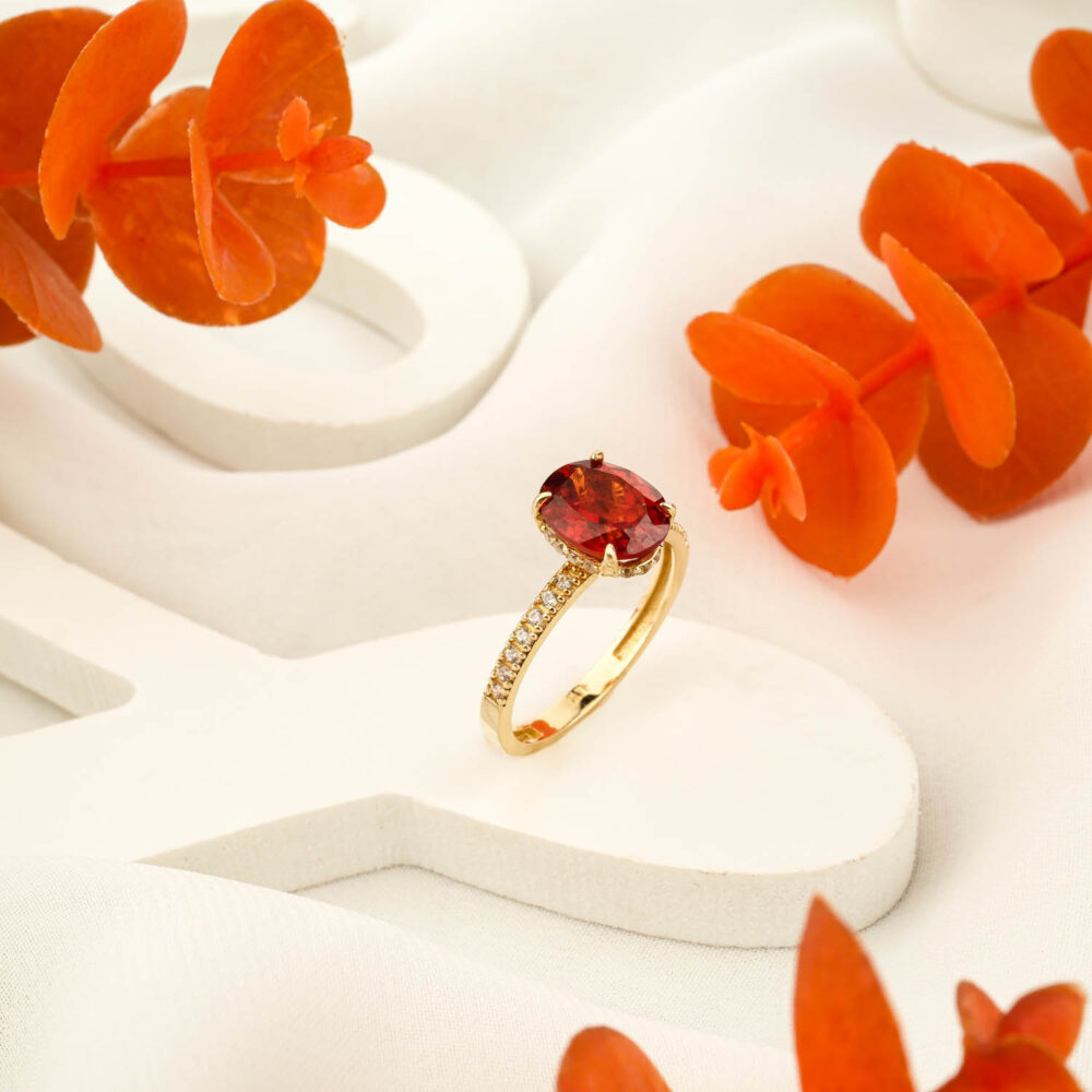Oval fire garnet ring in 14K gold with diamond accents on display