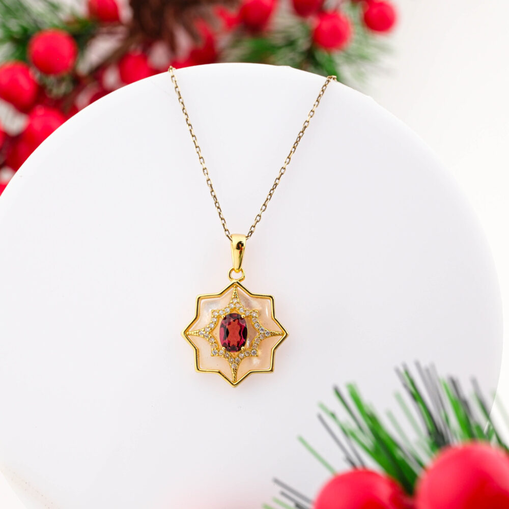 A gold-plated 925 sterling silver necklace featuring an eight-pointed star design with Mother of Pearl and a central Garnet stone.