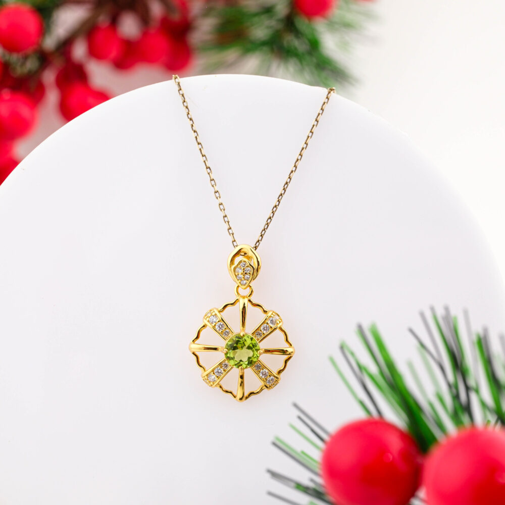 A gold-plated 925 sterling silver necklace featuring a round green Peridot and Swarovski crystals in a sun wheel design.