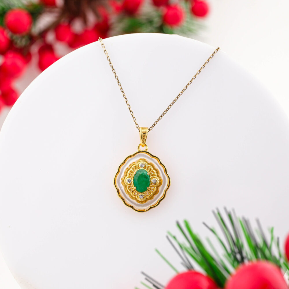 A gold-plated 925 sterling silver necklace featuring a central oval Zambian Emerald surrounded by mother of pearl and Swarovski crystals.