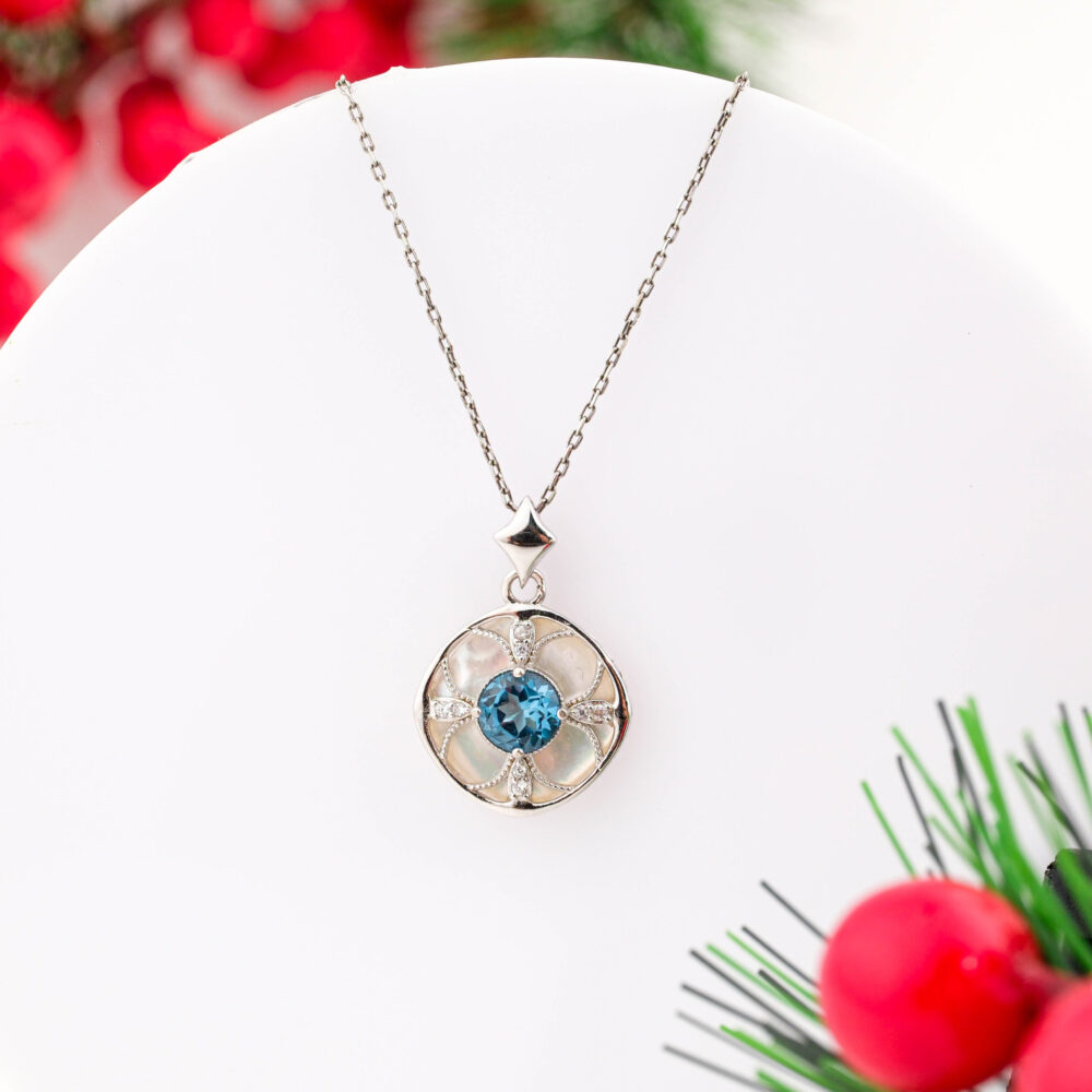 A designer 925 sterling silver necklace featuring a round floral pendant with a central Blue Topaz and Mother of Pearl background.