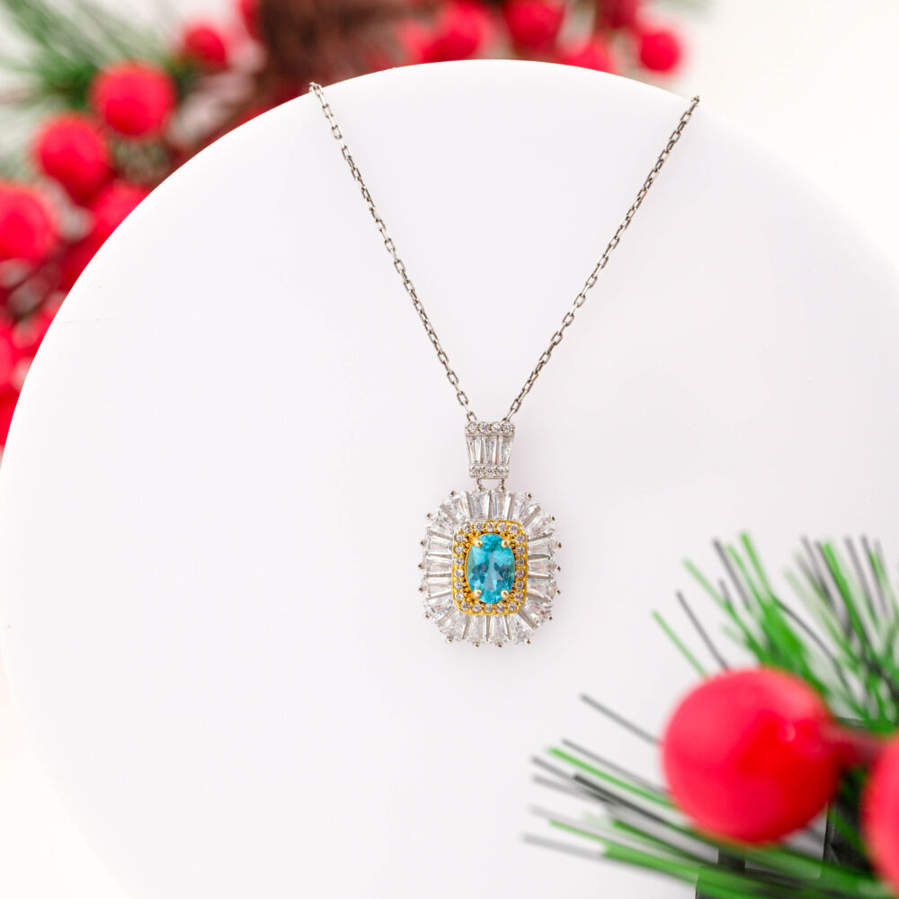 A designer 925 sterling silver necklace featuring an oval Blue Topaz surrounded by a large sunburst halo of baguette Swarovski crystals.