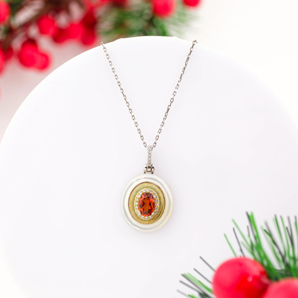 A designer 925 sterling silver necklace featuring a round pendant with an Orange Sapphire, gold sunburst, and Mother of Pearl border.