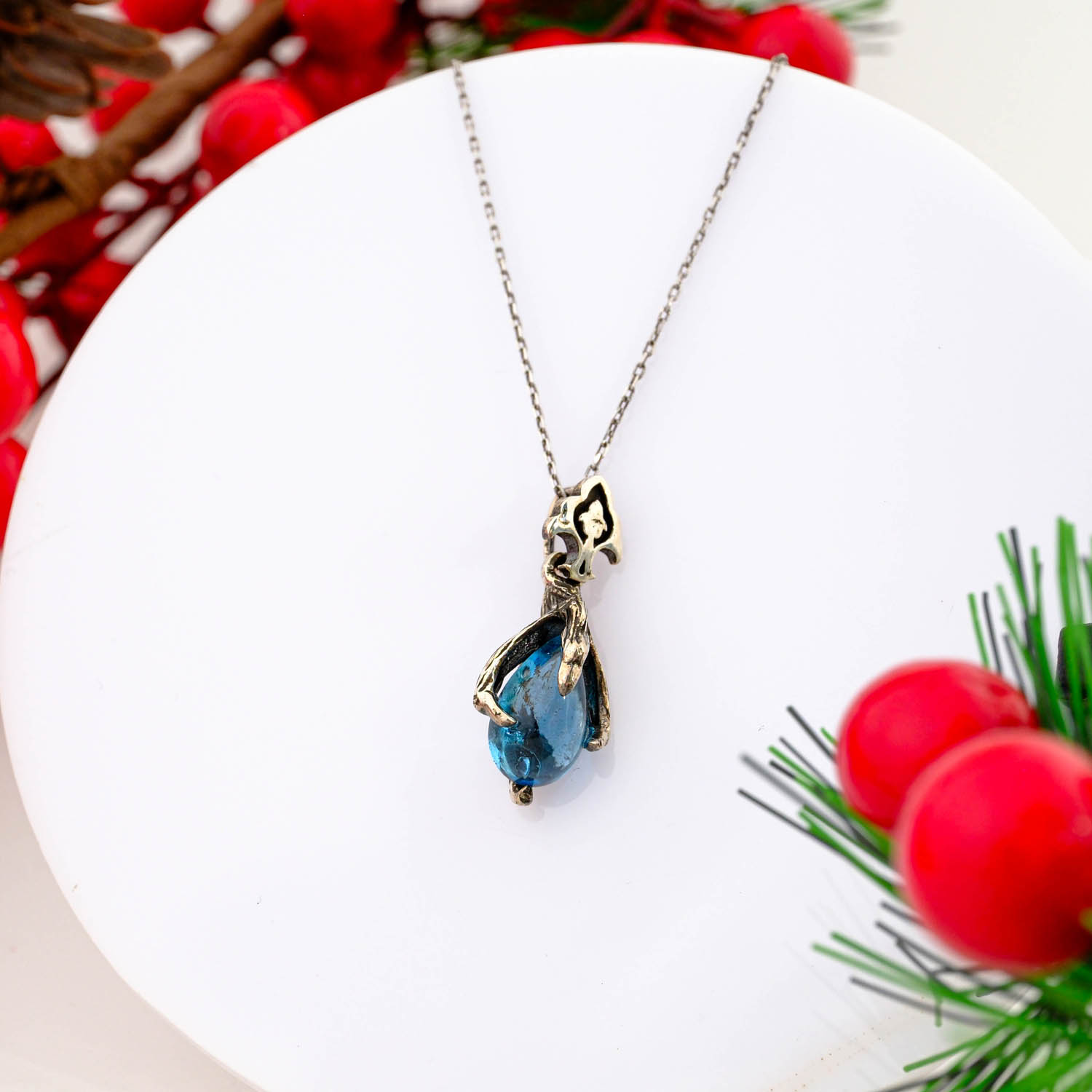 925 sterling silver pendant necklace featuring a natural pear cut blue topaz held by an oxidized organic vine setting