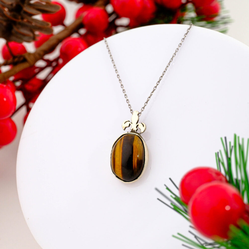 925 sterling silver pendant necklace featuring a natural oval tiger's eye stone with a heraldic fleur-de-lis bail design