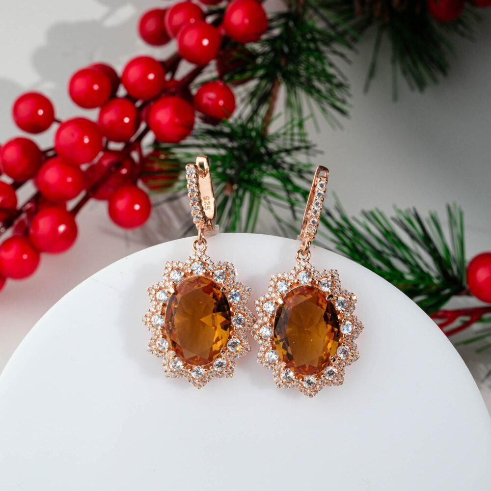 Rose gold plated 925 sterling silver drop earrings featuring a color changing oval cut zultanite stone surrounded by a sparkling sunburst crystal halo