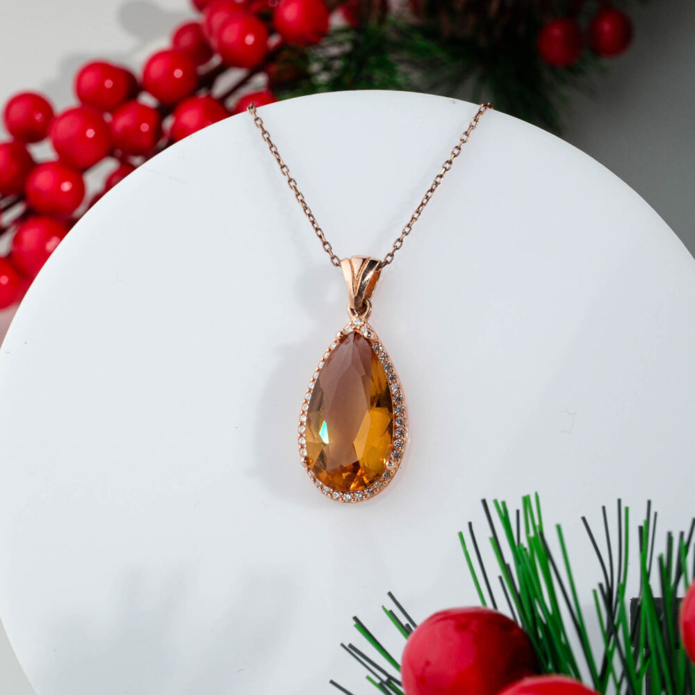 Rose gold plated 925 sterling silver necklace featuring a color changing pear cut zultanite pendant surrounded by a sparkling crystal halo